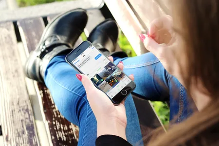 Photo of a person in jeans holding a phone showing a keyboard app.