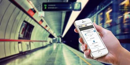 Hand holding an iPhone with a taxi app in a blurred subway tunnel.