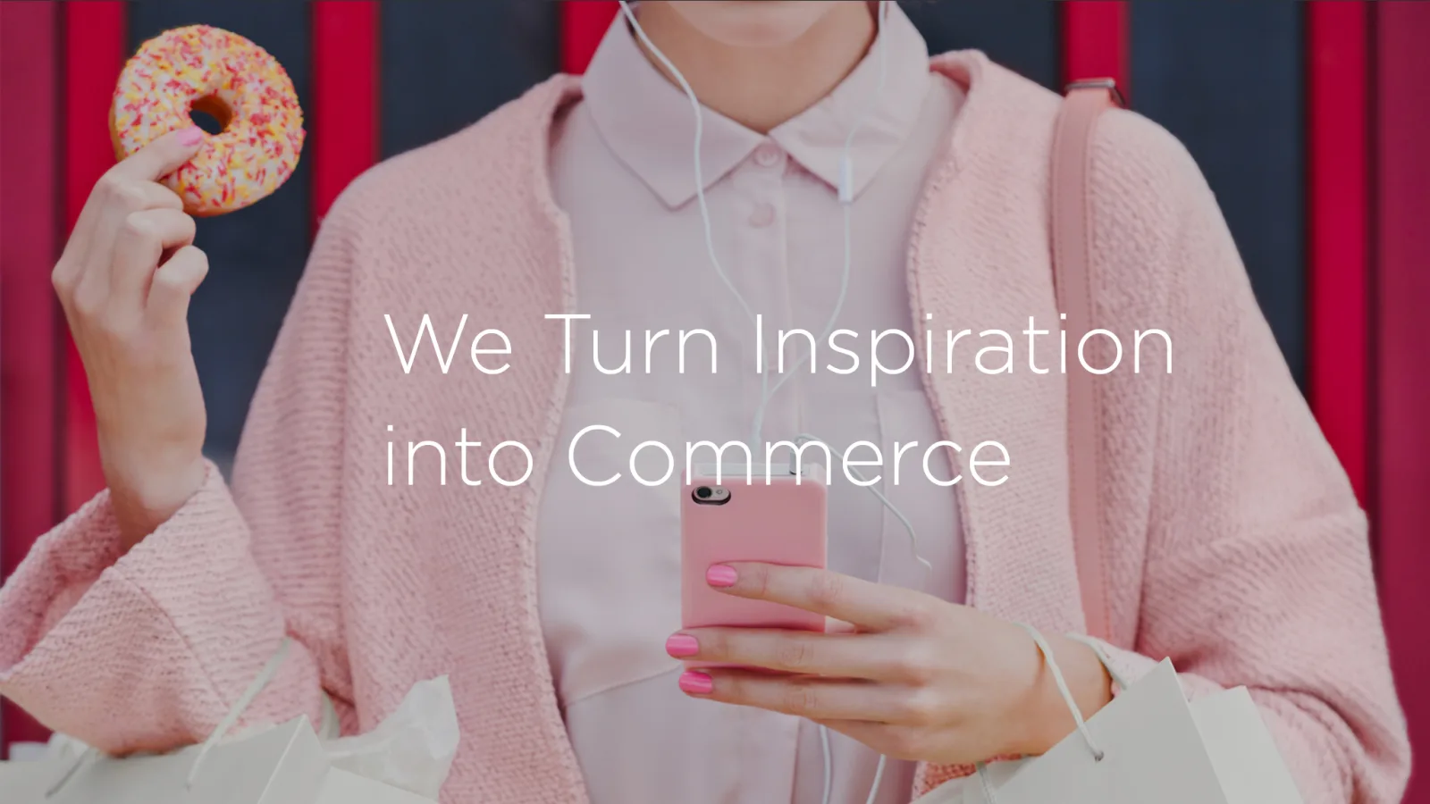 Woman in a pink cardigan holding a donut and a phone, overlaid with 'We Turn Inspiration into Commerce'.