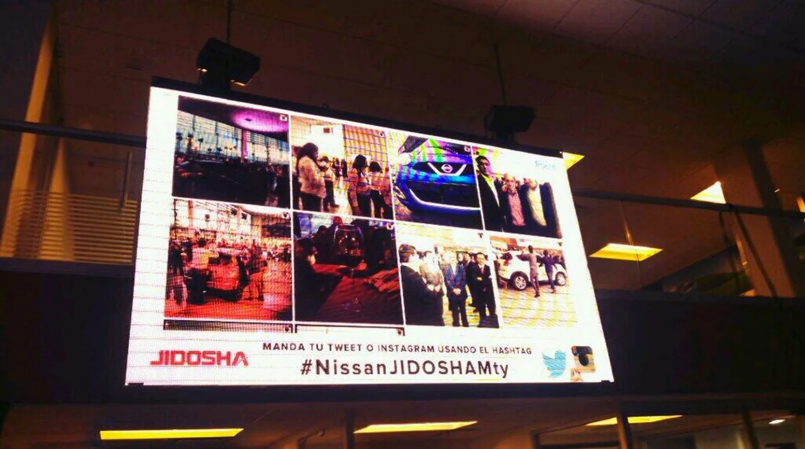 Photo of an LED screen at an event showing an Instagram photo wall and '#NissanJIDOSHAMty'.