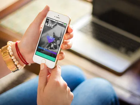 Hands holding an iPhone showing an app screen with a rating card.