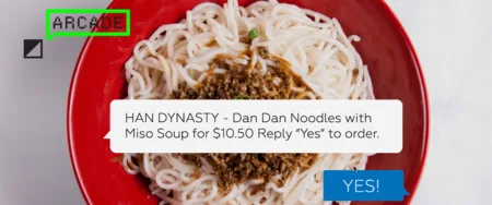 Bowl of noodles with an overlaid text message offering Dan Dan Noodles for $10.50 and a 'YES!' button.